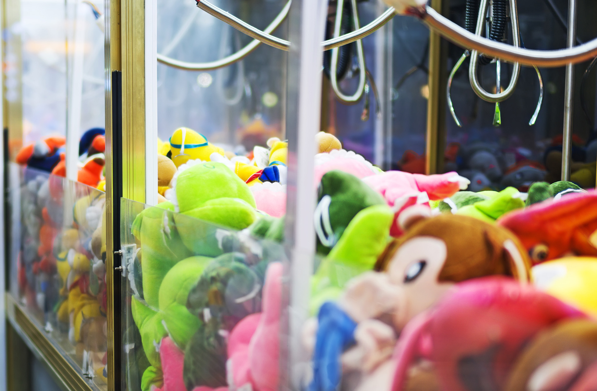 Mechanical claw game machine. Close-up view. arcade claw over different toys