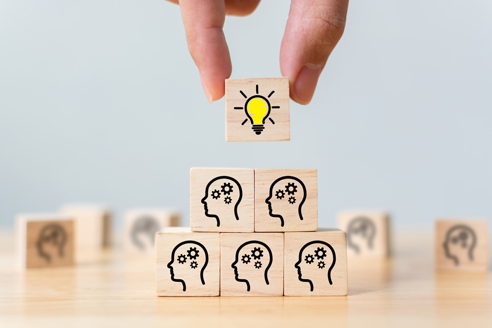 Concept creative idea and innovation. Hand picked wooden cube block with head human symbol and light bulb icon block pyramid