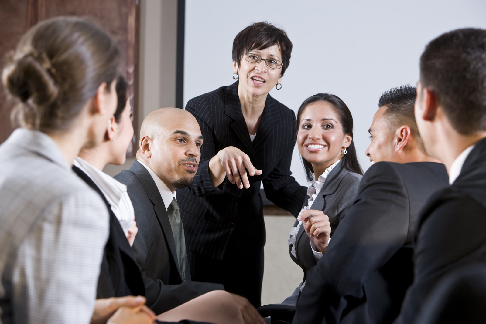 Diverse businesspeople conversing, woman at front group of professionals haing a discussion